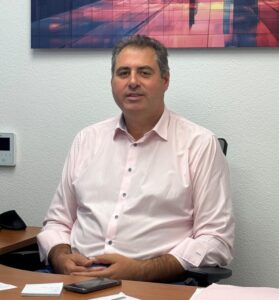 Hombre sentado ante un escritorio con documentos y un teléfono móvil.