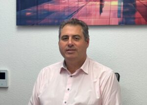 Hombre sentado ante un escritorio con documentos y un teléfono móvil.