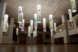 Instalación de acuarela con cilindros iluminados en una sala de exposición