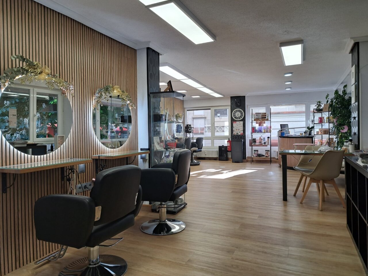Interior de una peluquería con sillones, espejos, mostrador y productos de cuidado capilar.