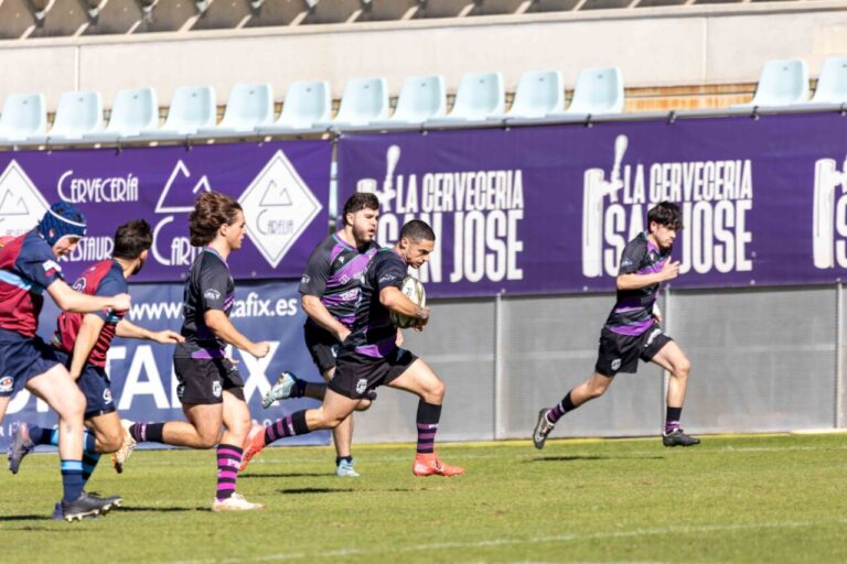 Jugador de rugby corre con el balón mientras varios jugadores lo siguen en el campo.