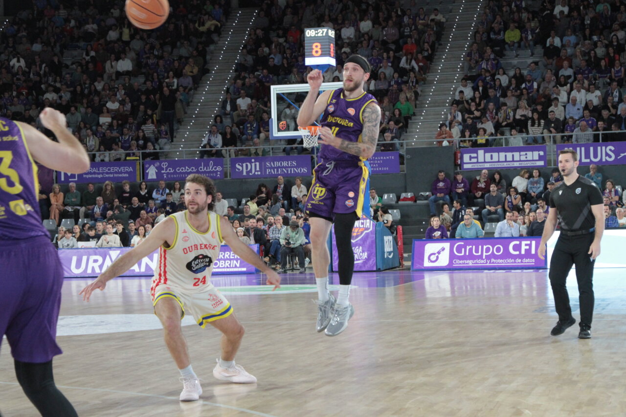 Jugador de baloncesto con uniforme morado salta mientras otro jugador defiende.
