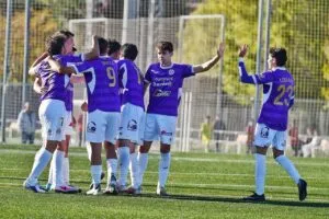 Futbolistas con uniforme morado celebran juntos en un campo de fútbol