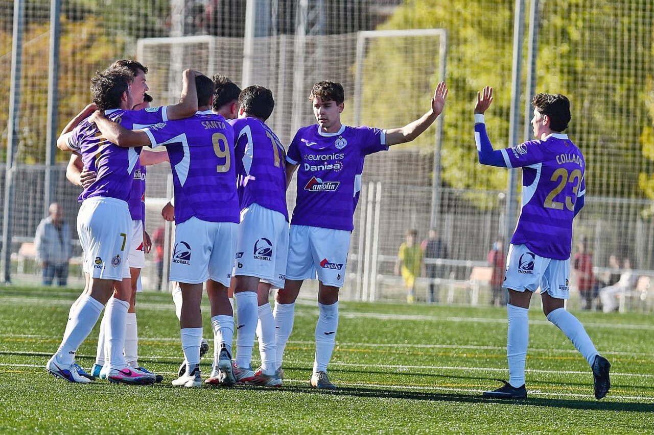 Futbolistas con uniforme morado celebran juntos en un campo de fútbol