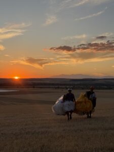 Dos personas caminando con parapentes al atardecer en un campo