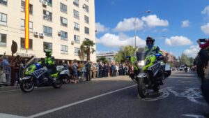 Dos motoristas de la Guardia Civil de Tráfico circulan ante una multitud en una calle.