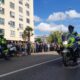 Dos motoristas de la Guardia Civil de Tráfico circulan ante una multitud en una calle.