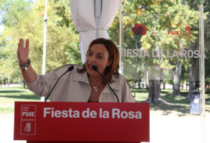 Mujer habla ante un atril del PSOE durante la Fiesta de la Rosa.