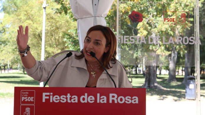 Mujer habla ante un atril del PSOE durante la Fiesta de la Rosa.