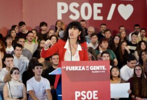 Una mujer habla desde un atril del PSOE ante un público sentado.