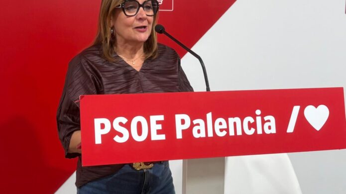 Mujer con gafas junto a un micrófono tras un atril del PSOE Palencia