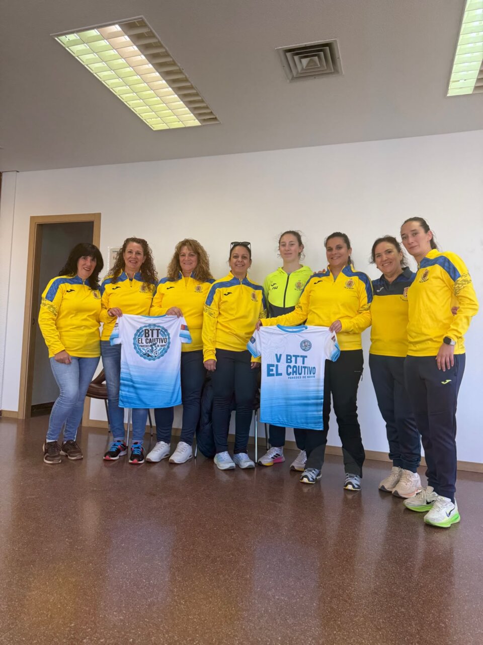 Ocho mujeres posan en una sala con camisetas de la V BTT El Cautivo