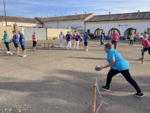Varias mujeres juegan a los bolos en una cancha al aire libre.