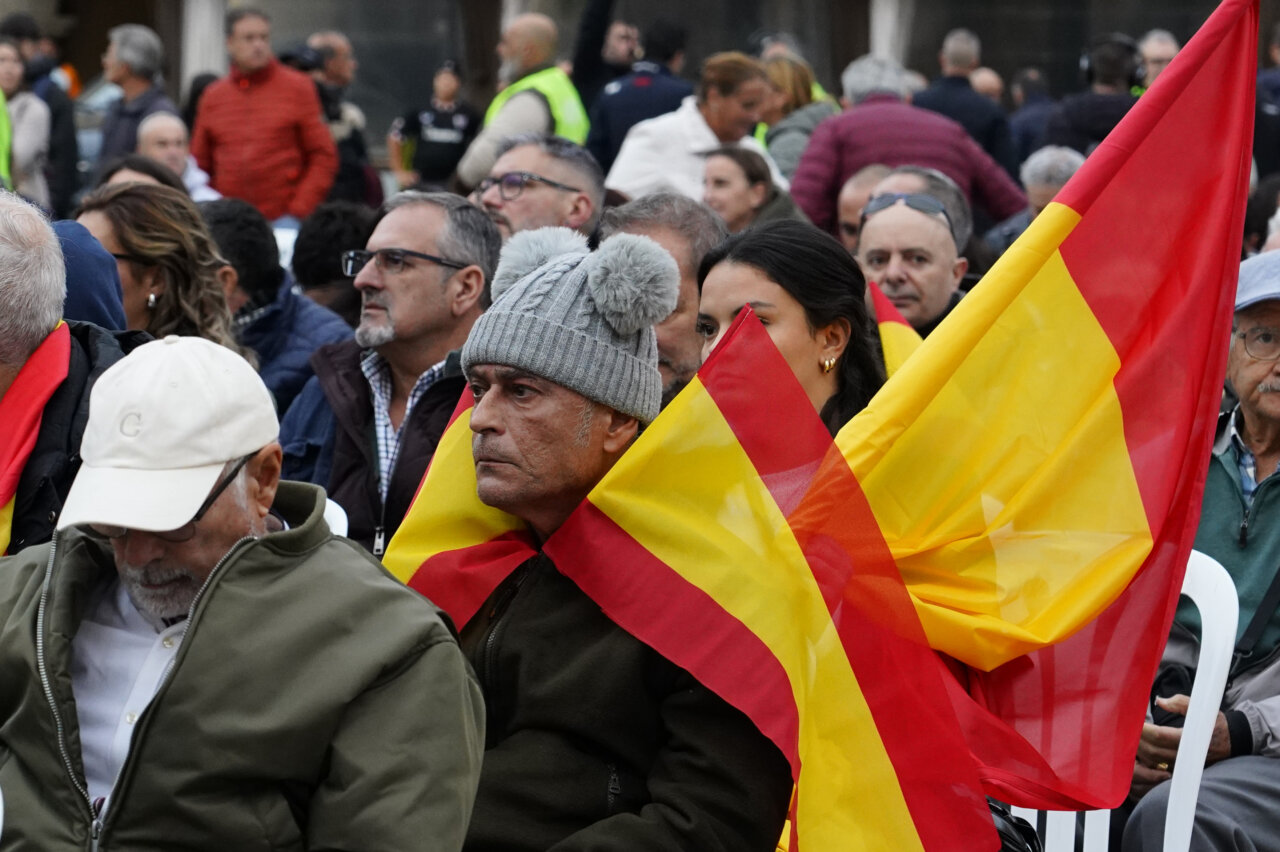 Personas entre una multitud sostienen varias banderas españolas.
