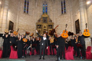 Grupo de músicos posa con instrumentos de cuerda pulsada frente a un retablo.