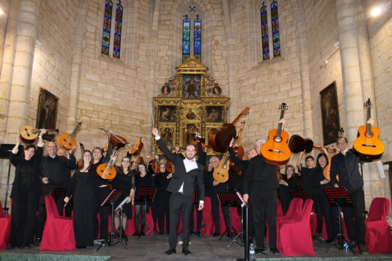 Grupo de músicos posa con instrumentos de cuerda pulsada frente a un retablo.