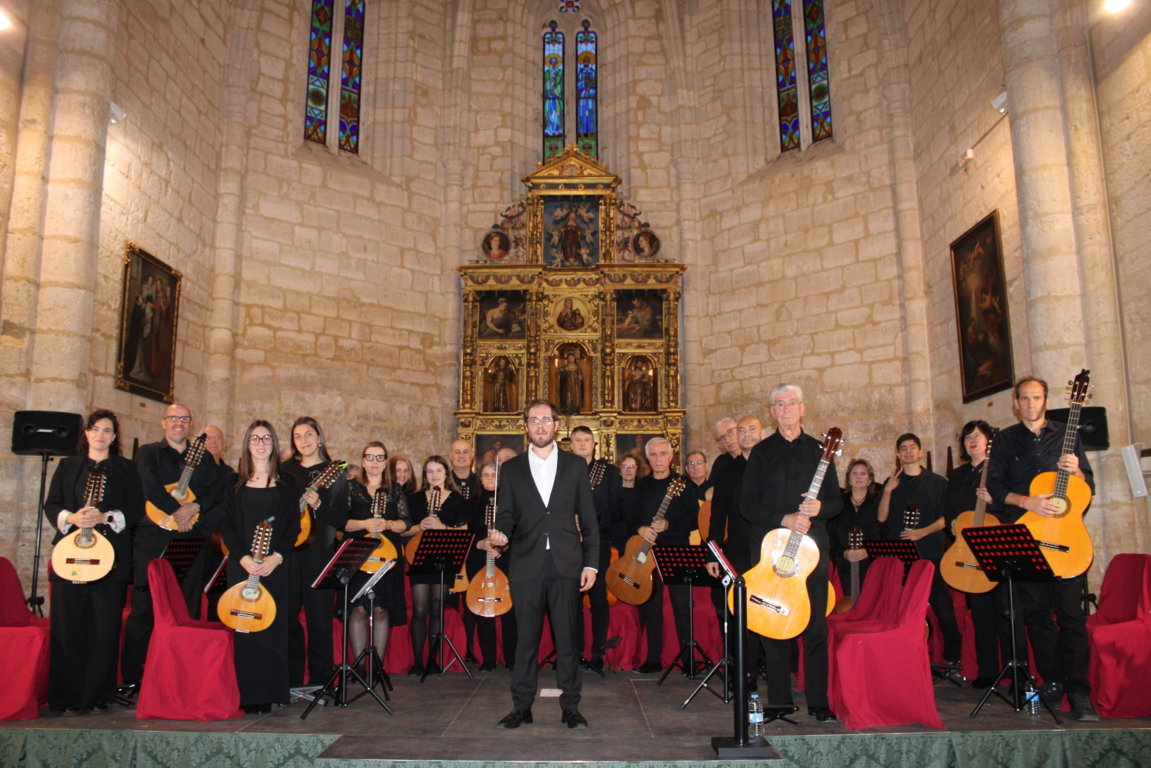 Grupo de músicos con instrumentos de cuerda pulsada posa ante un retablo en una iglesia