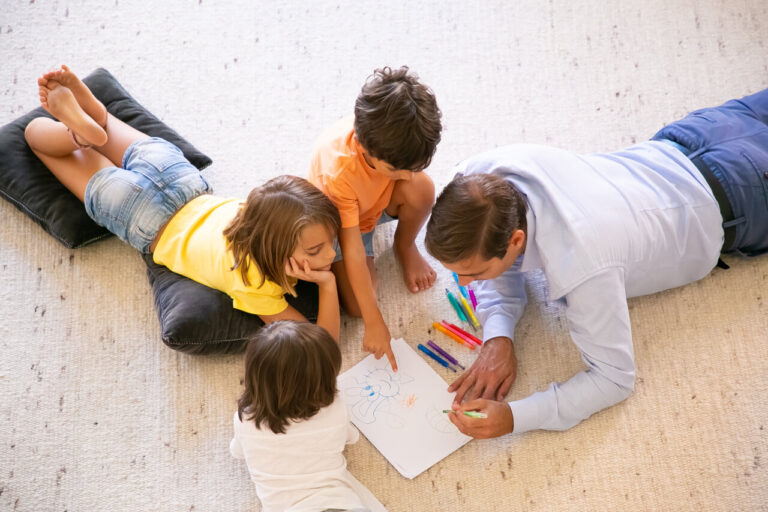 Padre con niños dibujando en una alfombra en casa