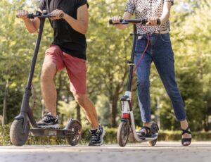 Pareja joven disfrutando de un paseo en scooters eléctricos en un parque