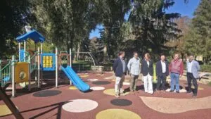 Varias personas junto a una estructura de juegos infantiles en un parque arbolado