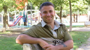 Joven sonriendo en un parque con juegos infantiles al fondo