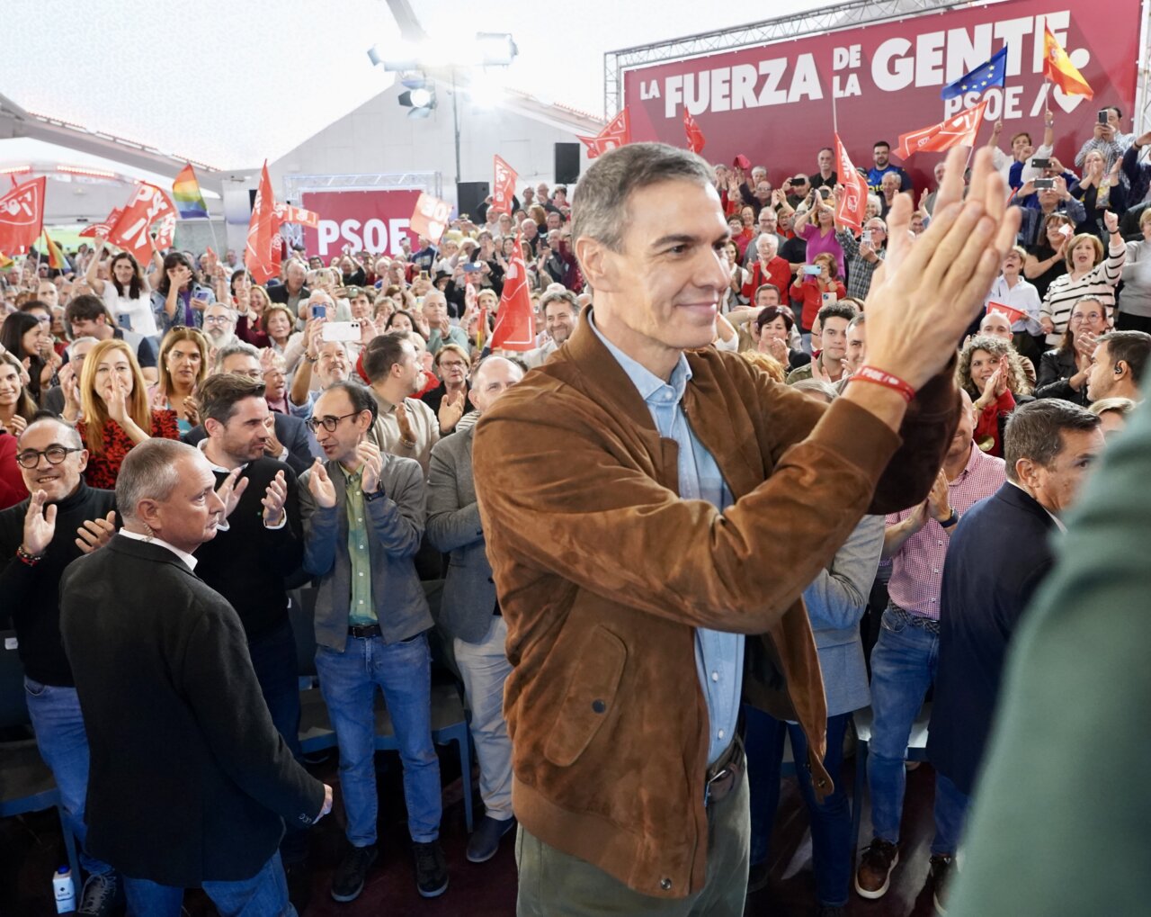 Pedro Sánchez aplaude ante una multitud en un acto con banderas del PSOE.