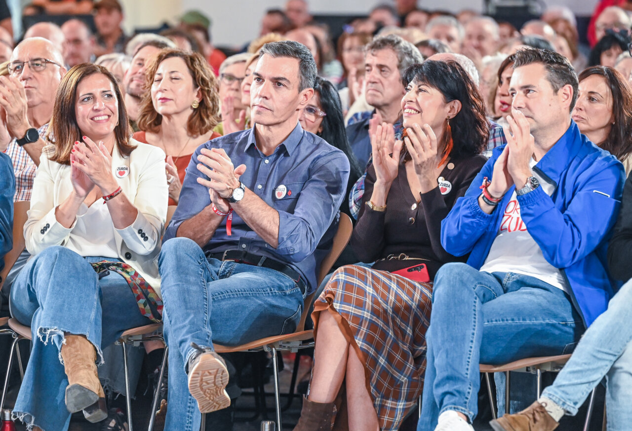 Pedro Sánchez y otros asistentes aplauden sentados durante un acto político.