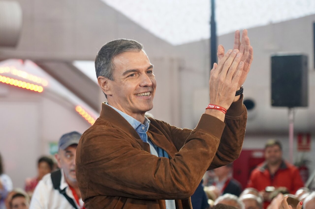 Pedro Sánchez aplaude durante un acto, con una pulsera roja del PSOE en la muñeca.