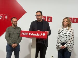 Tres personas junto a un atril del PSOE Palencia durante una comparecencia.