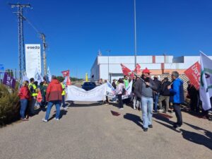 Personas con banderas y una pancarta se concentran ante una nave industrial de Seda.