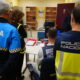 Varias personas con chalecos policiales observan un escritorio y un ordenador en una oficina.