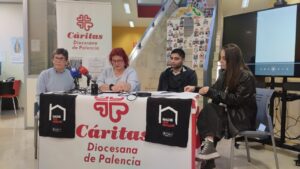 Cuatro personas sentadas ante micrófonos en una mesa con distintivos de Cáritas Palencia