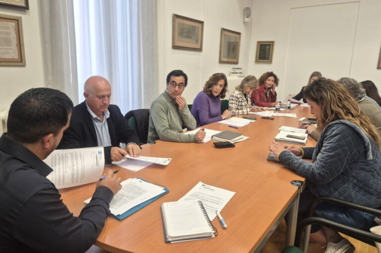 Varias personas sentadas alrededor de una mesa con documentos durante una reunión.