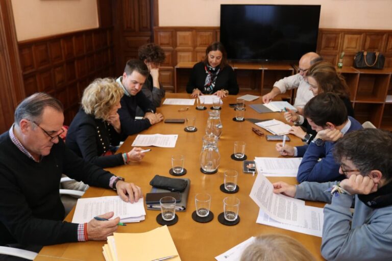Varias personas revisan documentos sentadas alrededor de una mesa de reuniones.