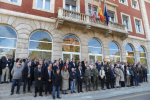 Grupo de personas reunido ante un edificio institucional con banderas en la fachada.