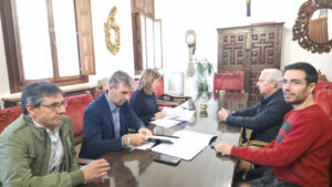 Varias personas revisan documentos alrededor de una mesa en una sala.