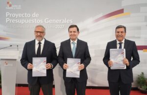 Tres hombres sosteniendo un documento sobre presupuestos en un evento oficial