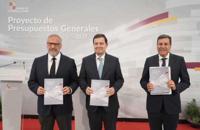 Tres hombres sosteniendo un documento sobre presupuestos en un evento oficial