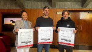 Tres personas sostienen carteles del festival Terroríficamente Cortos en una sala.