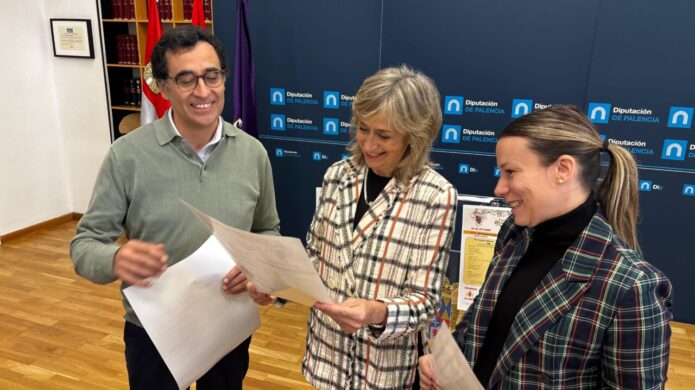 Tres personas revisan documentos ante un panel de la Diputación de Palencia.