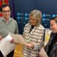 Tres personas revisan documentos ante un panel de la Diputación de Palencia.