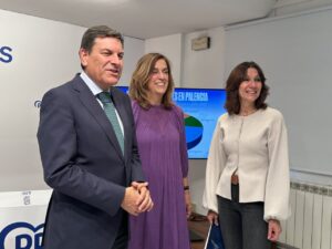 Tres personas posan frente a una pantalla con una presentación sobre presupuestos en Palencia.