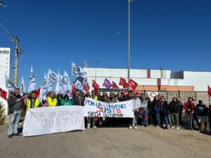 Grupo de personas sostiene pancartas sindicales frente a un edificio industrial