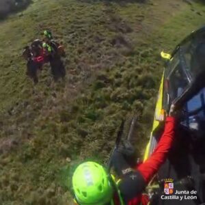 Varias personas se agrupan en una ladera junto a un helicóptero.