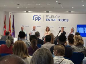 Personas sentadas en una sala escuchan a varios participantes en una mesa del PP Palencia.