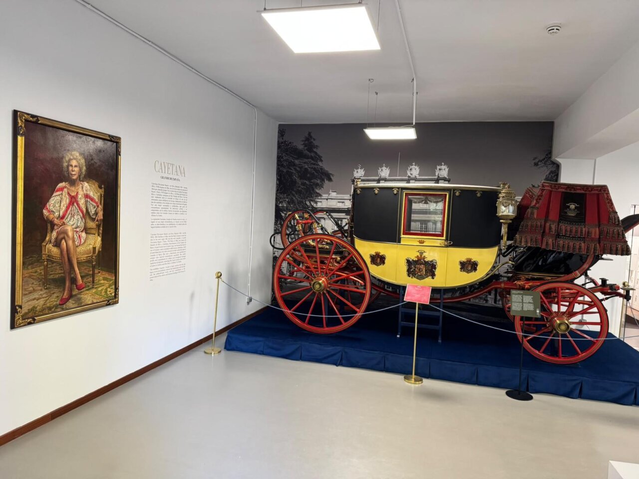 Fotografía de una sala con retrato de Cayetana y un carruaje antiguo expuesto.