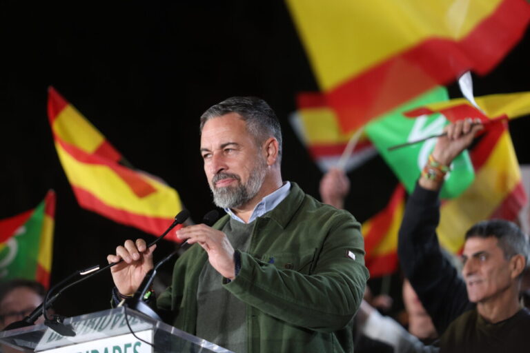 Santiago Abascal habla ante micrófonos con banderas de España y Vox al fondo