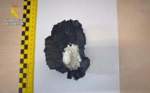 Sustancia blanca envuelta en plástico negro junto a una regla de medición.