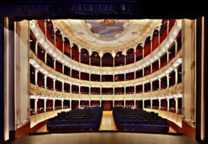 Vista desde el escenario de un teatro vacío con palcos ornamentados y butacas