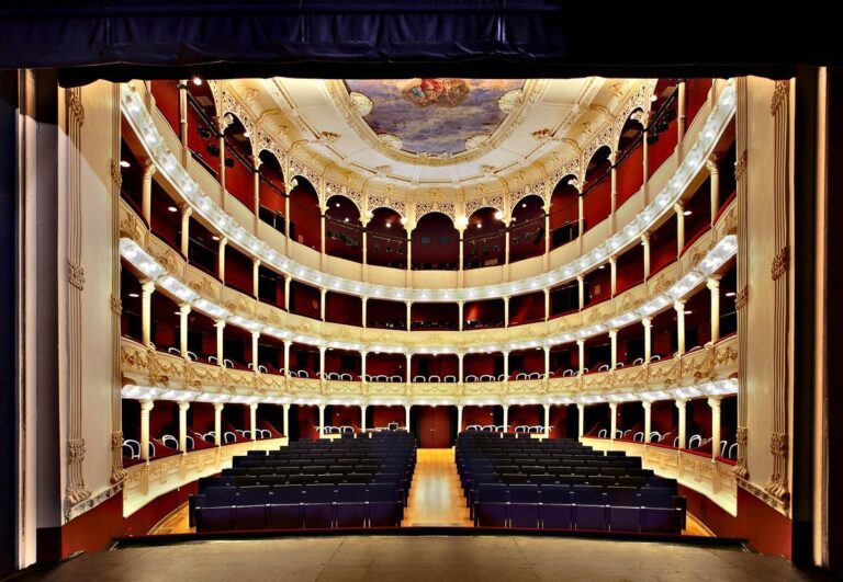 Vista desde el escenario de un teatro vacío con palcos ornamentados y butacas